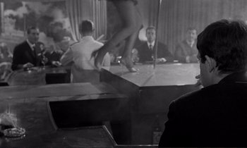 Movie still from “Le Doulos” (1962), directed by Jean-Pierre Melville – A group of people sitting around a table; Medium shot, Over the shoulder angle