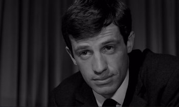Movie still from “Le Doulos” (1962), directed by Jean-Pierre Melville – Black and white photograph of a man in a suit; Close Up shot, Low angle
