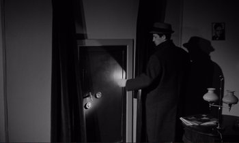 Movie still from “Le Doulos” (1962), directed by Jean-Pierre Melville – A man standing in front of an open door; Medium shot, High angle