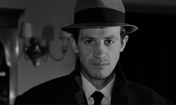 Movie still from “Le Doulos” (1962), directed by Jean-Pierre Melville – A black and white photo of a man wearing a hat; Close Up shot, Low angle