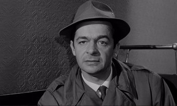 Movie still from “Le Doulos” (1962), directed by Jean-Pierre Melville – A man wearing a hat and a raincoat; Close Up shot, High angle