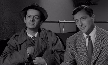 Movie still from “Le Doulos” (1962), directed by Jean-Pierre Melville – A black and white photo of two men sitting next to each other; Medium shot, High angle