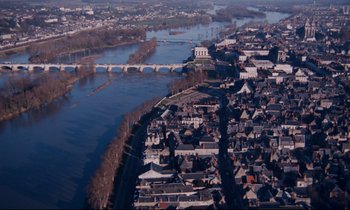 Movie still from “Le Grand Amour” (1969), directed by Pierre Étaix – An aerial view of a city with a bridge in the background; Extreme Wide shot, High angle