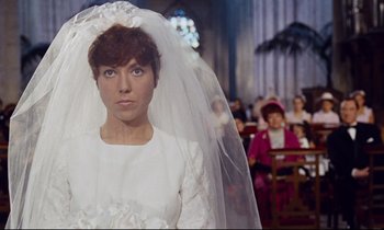 Movie still from “Le Grand Amour” (1969), directed by Pierre Étaix – A woman wearing a wedding dress in a church; Close Up shot, High angle