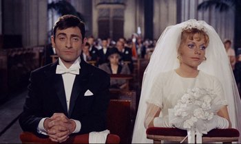 Movie still from “Le Grand Amour” (1969), directed by Pierre Étaix – A man and a woman sitting at a wedding ceremony; Medium shot, High angle
