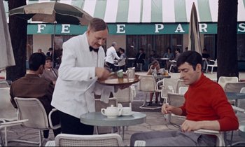 Movie still from “Le Grand Amour” (1969), directed by Pierre Étaix – A waiter is serving a customer at an outdoor cafe; Medium shot, High angle
