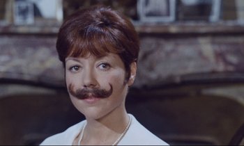 Movie still from “Le Grand Amour” (1969), directed by Pierre Étaix – A woman with a fake mustache on her face; Close Up shot, Low angle