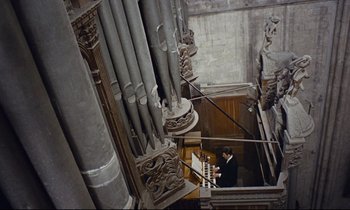 Movie still from “Le Grand Amour” (1969), directed by Pierre Étaix – A man standing in front of an organ in a church; Extreme Wide shot, Overhead angle
