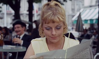 Movie still from “Le Grand Amour” (1969), directed by Pierre Étaix – A woman is looking down at a menu in a restaurant; Close Up shot, Over the shoulder angle