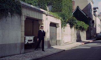 Movie still from “Le Grand Amour” (1969), directed by Pierre Étaix – A man standing in front of a garage door; Wide shot, Low angle