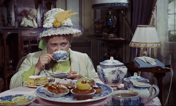 Movie still from “Le Grand Amour” (1969), directed by Pierre Étaix – An old lady drinking tea at a tea party; Medium shot, High angle