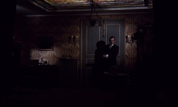 Movie still from “Le Grand Amour” (1969), directed by Pierre Étaix – A man standing in a dark room next to a door; Wide shot, High angle