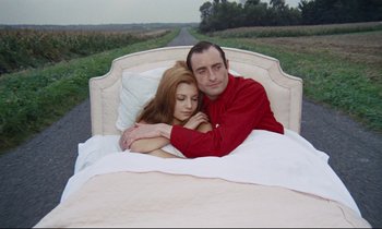 Movie still from “Le Grand Amour” (1969), directed by Pierre Étaix – A man and a woman laying in a bed together; Medium shot, High angle