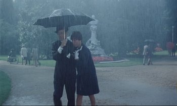 Movie still from “Le Grand Amour” (1969), directed by Pierre Étaix – A man and a woman under an umbrella in the rain; Wide shot, Low angle