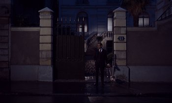 Movie still from “Le Grand Amour” (1969), directed by Pierre Étaix – A man standing in front of an entrance to a building; Wide shot, Low angle