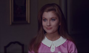 Movie still from “Le Grand Amour” (1969), directed by Pierre Étaix – A woman in a pink dress is smiling for the camera; Close Up shot, Over the shoulder angle