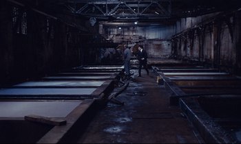 Movie still from “Le Grand Amour” (1969), directed by Pierre Étaix – Two men are standing in an industrial setting; Wide shot, High angle
