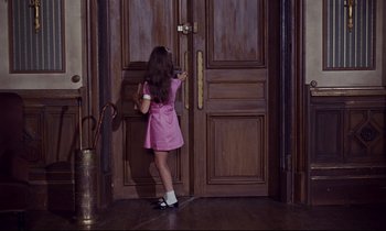 Movie still from “Le Grand Amour” (1969), directed by Pierre Étaix – A little girl in a pink dress standing in front of a door; Wide shot, High angle