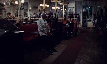 Movie still from “Le Grand Amour” (1969), directed by Pierre Étaix – Two people sitting on a bench in a restaurant; Wide shot, High angle