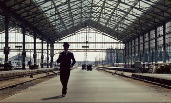Movie still from “Le Grand Amour” (1969), directed by Pierre Étaix – A man is walking down a train station platform; Extreme Wide shot, Low angle