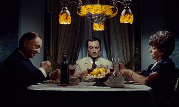Movie still from “Le Grand Amour” (1969), directed by Pierre Étaix – A group of people sitting around a dinner table; Medium shot, High angle