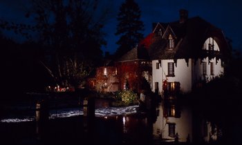 Movie still from “Le Grand Amour” (1969), directed by Pierre Étaix – A house is lit up at night by the water; Extreme Wide shot, High angle