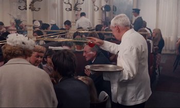 Movie still from “Le Grand Amour” (1969), directed by Pierre Étaix – A group of people sitting at a table with trays of food on it; Medium shot, High angle
