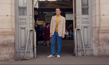 Movie still from “Le Grand Amour” (1969), directed by Pierre Étaix – A man standing in front of an entrance to a building; Wide shot, Low angle