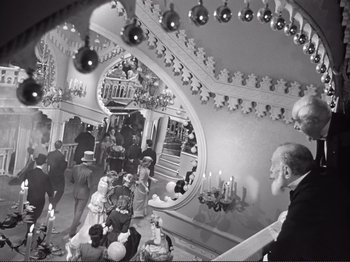 Movie still from “Le Plaisir” (1952), directed by Max Ophüls – A black and white photo of a man looking in a mirror; Wide shot, High angle