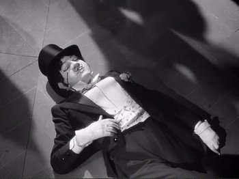 Movie still from “Le Plaisir” (1952), directed by Max Ophüls – A mime is laying on the ground wearing a top hat; Medium shot, High angle