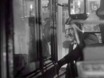 Movie still from “Le Plaisir” (1952), directed by Max Ophüls – A black and white photo of a man looking out of a window; Medium shot, Over the shoulder angle
