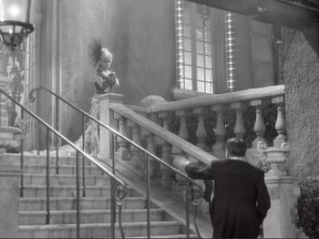 Movie still from “Le Plaisir” (1952), directed by Max Ophüls – An old photo of a man and a woman on a staircase; Wide shot, Low angle