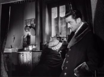 Movie still from “Le Plaisir” (1952), directed by Max Ophüls – A black and white photo of a man and a woman in a kitchen; Medium shot, Over the shoulder angle