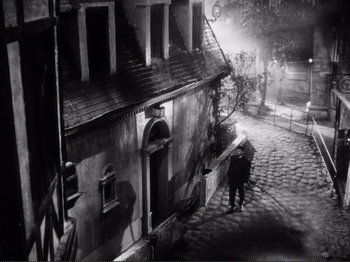 Movie still from “Le Plaisir” (1952), directed by Max Ophüls – Two people walking down a street at night; Extreme Wide shot, High angle