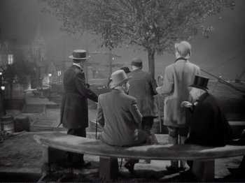 Movie still from “Le Plaisir” (1952), directed by Max Ophüls – A black and white photo of a group of men sitting on top of a bench; Wide shot, High angle