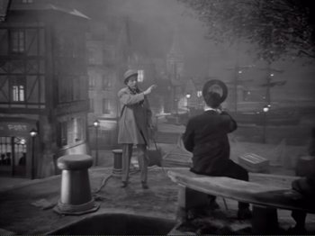 Movie still from “Le Plaisir” (1952), directed by Max Ophüls – A man and a woman are standing on a bench; Wide shot, High angle