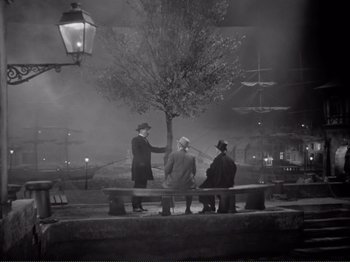 Movie still from “Le Plaisir” (1952), directed by Max Ophüls – A group of men sitting on a bench at night; Wide shot, High angle