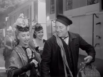 Movie still from “Le Plaisir” (1952), directed by Max Ophüls – A man and two women are walking together; Medium shot, Over the shoulder angle
