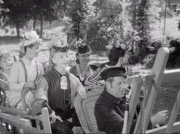 Movie still from “Le Plaisir” (1952), directed by Max Ophüls – A black and white photo of a group of people sitting in chairs; Medium shot, Low angle