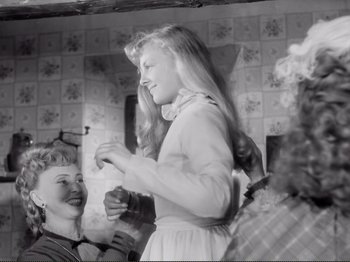 Movie still from “Le Plaisir” (1952), directed by Max Ophüls – A young girl standing in front of a group of people; Medium shot, Over the shoulder angle