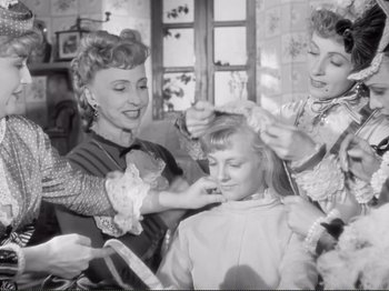 Movie still from “Le Plaisir” (1952), directed by Max Ophüls – A group of women are combing a young girl's hair; Medium shot, High angle