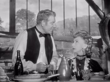Movie still from “Le Plaisir” (1952), directed by Max Ophüls – An old photo of a man and a woman sitting at a dinner table; Medium shot, Over the shoulder angle