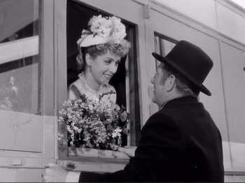 Movie still from “Le Plaisir” (1952), directed by Max Ophüls – An older man and a woman looking out of a window; Medium shot, Over the shoulder angle