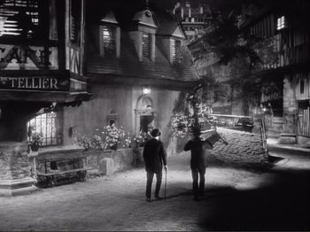 Movie still from “Le Plaisir” (1952), directed by Max Ophüls – Two people walking down a street at night; Extreme Wide shot, High angle