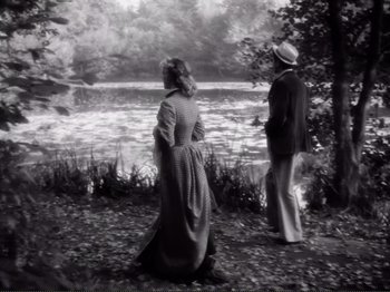 Movie still from “Le Plaisir” (1952), directed by Max Ophüls – A man and a woman standing next to a body of water; Wide shot, High angle