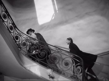 Movie still from “Le Plaisir” (1952), directed by Max Ophüls – Two men are walking down a staircase in black and white; Wide shot, High angle