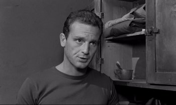 Movie still from “The Hole” (1960), directed by Jacques Becker – Black and white photograph of a man in front of an open cabinet; Close Up shot, Low angle