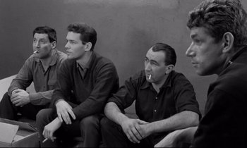Movie still from “The Hole” (1960), directed by Jacques Becker – A group of men sitting next to each other; Medium shot, High angle