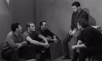 Movie still from “The Hole” (1960), directed by Jacques Becker – A black and white photo of a group of men sitting in a circle; Medium shot, High angle