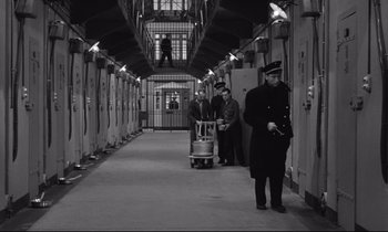 Movie still from “The Hole” (1960), directed by Jacques Becker – A group of men walking down a train platform; Wide shot, High angle